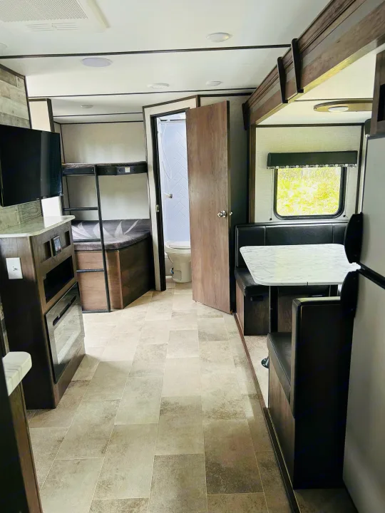 Explore this RV rental's spacious interior: dinette, bunk beds, kitchen area, and a full bathroom for comfortable journeys.. Dutchmen Coleman Light 2021
