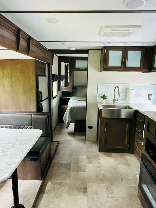 Modern RV rental interior with a fully equipped kitchen, dining booth, and inviting bedroom. Perfect for your next trip!. Dutchmen Coleman Light 2021