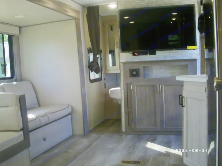This modern RV rental interior features a cozy living area with light-colored seating, a wall-mounted TV, and light wood flooring.. COACHMAN CATALINA 261BHS 2024