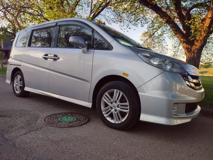 Silver minivan, a versatile vehicle for your RV rental adventure, parked on asphalt near a large green tree.. Universal Transformer 2009