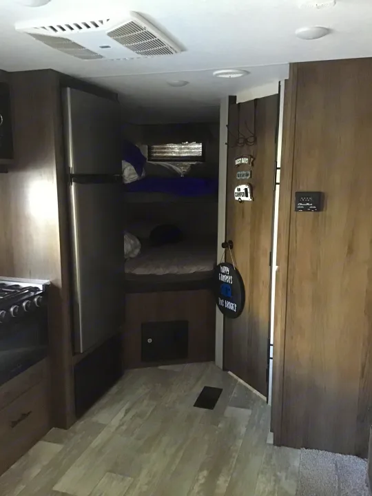 Explore this cozy RV rental interior: modern kitchen, spacious fridge, and comfortable bunk beds for your next adventure.. Prime Time Avenger 2021