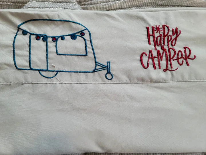 "Happy Camper" embroidered on fabric, showing a teal RV outline with red lights, ideal for an rv rental.. Jayco Jay Flight SLX Baja Edition 2021
