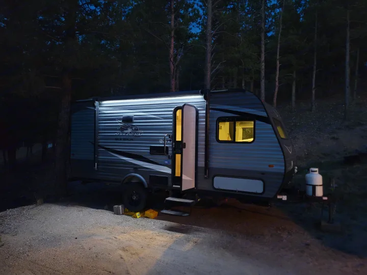 An RV rental is brightly lit at night, parked at a forest campsite. Ready for your camping adventure!. Jayco Jay Flight SLX Baja Edition 2021