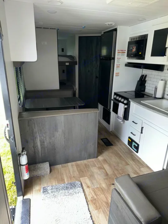 Interior of an RV rental featuring a well-equipped kitchen, dinette, and bunk beds. Bright and functional camper space.. Keystone Hideout 2022