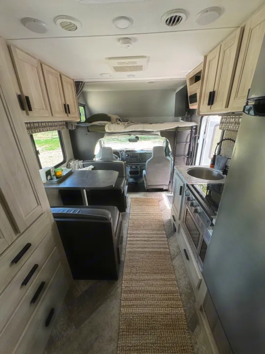 RV rental interior showcasing a full kitchenette, dinette, and overhead bunk. Perfect for road trips and comfortable stays.. Forest River Sunseeker LE 2021