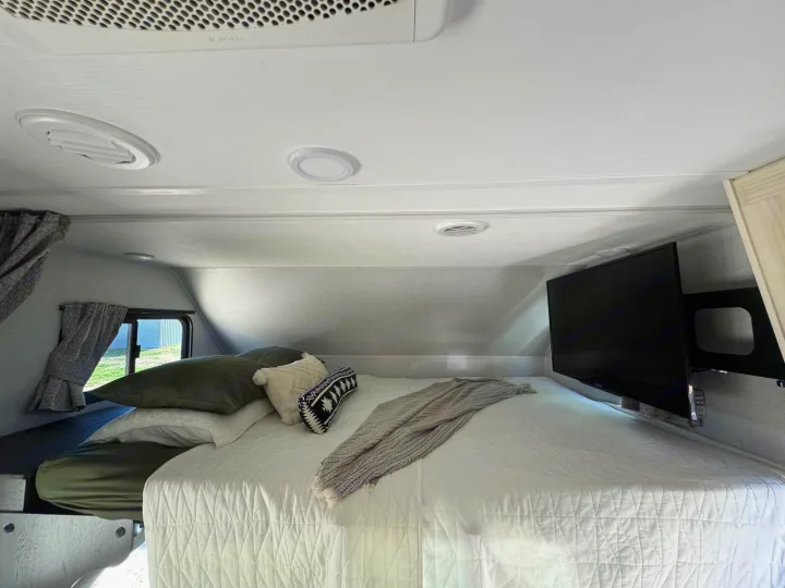 Comfortable RV rental bedroom with a large bed, TV, and window view. Perfect for your next trip!. Forest River Sunseeker LE 2021