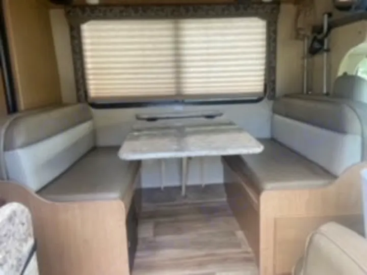This RV rental interior shows a spacious dinette with comfortable benches and a large window, ideal for travel.. Thor Four Winds 2020