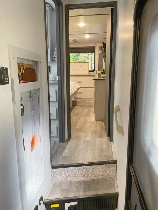Modern RV interior hallway leading to bedroom, with integrated key holder & step down. Ideal for an rv rental.. Keystone RV Montana High Country 2021