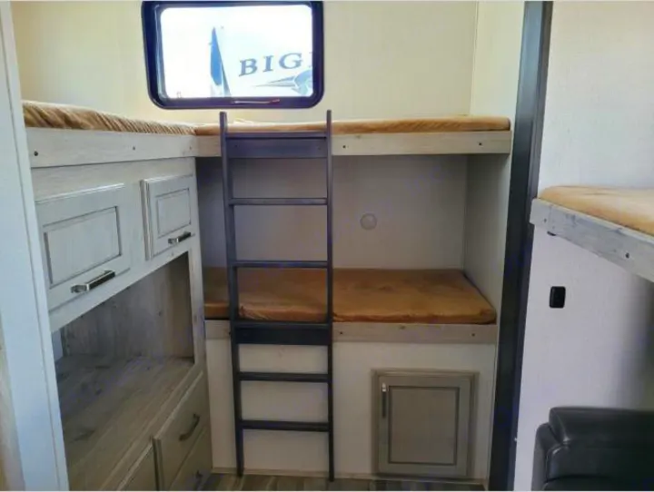 This RV rental showcases cozy bunk beds with built-in storage. Perfect for camper adventures.. Keystone RV Avalanche 2021