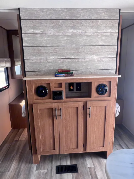 RV rental interior: Entertainment system, wood-look storage, and a bed area with a light wood panel.. Prime Time Avenger 24 BHS 2023