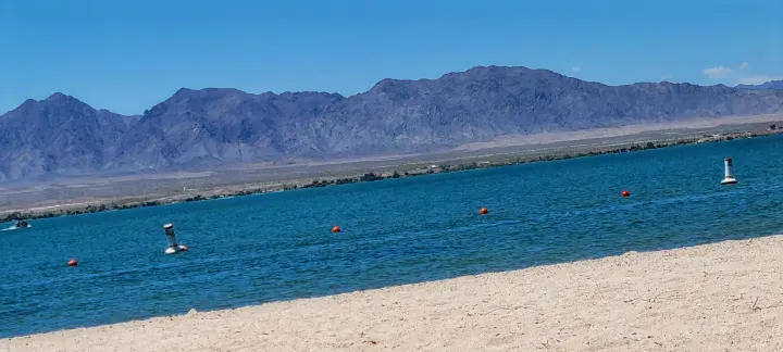 Expansive blue lake, sandy beach, and distant mountains with buoys & jet ski. Plan your RV rental adventure!. Thor Chateau 2016