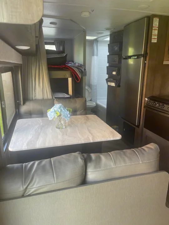 Spacious RV rental interior featuring a dinette, bunk beds, full kitchen, and compact bathroom with toilet and tub.. Forest River Wildwood X-Lite 2021