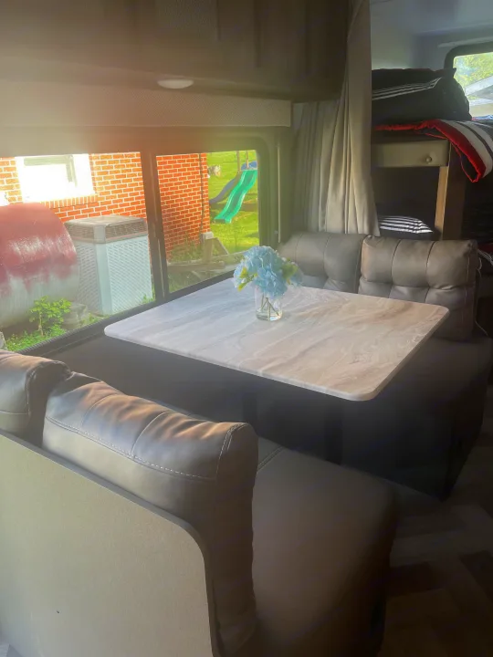 Cozy RV rental interior: bright dinette with a view of the outdoors, plus comfortable seating and bunk beds.. Forest River Wildwood X-Lite 2021