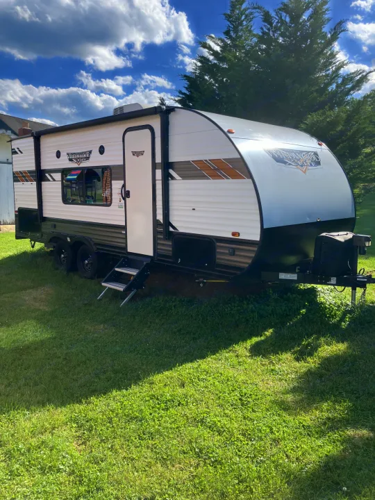 Explore with this Wildwood X-Lite RV rental! A bright white travel trailer is parked on a sunny green lawn, ready for adventure.. Forest River Wildwood X-Lite 2021