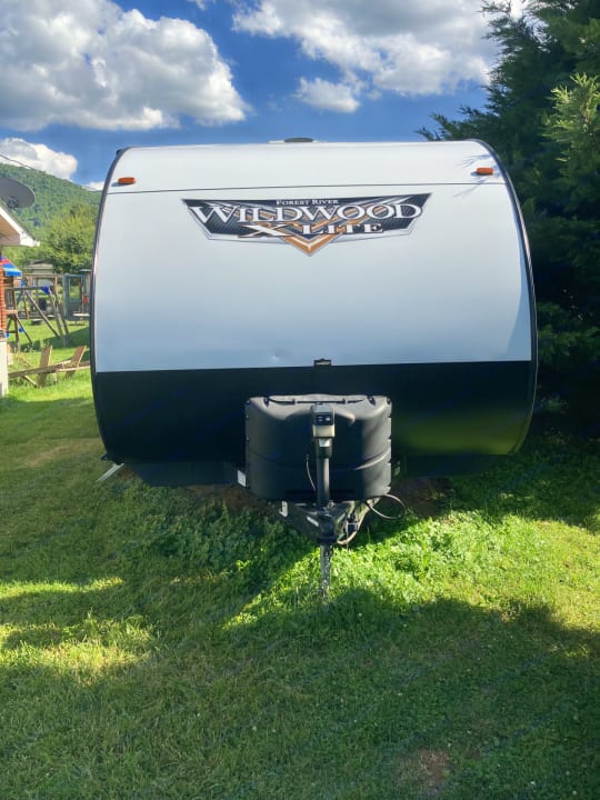 Front view of a white Forest River Wildwood Lite travel trailer, ideal for your next RV rental adventure in the outdoors.. Forest River Wildwood X-Lite 2021