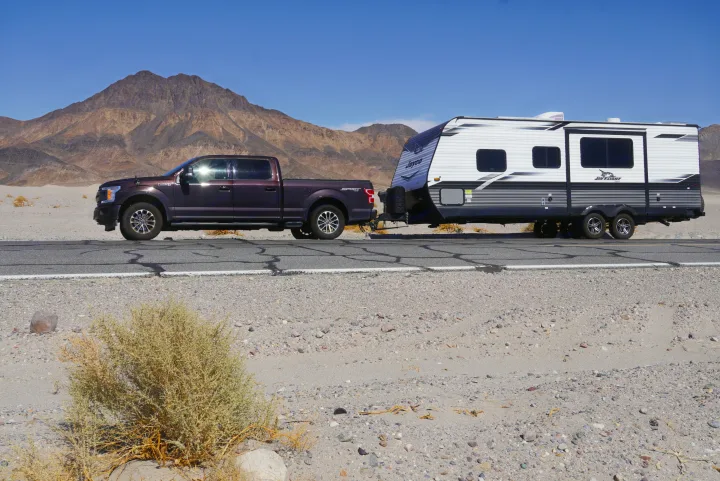 Towing an RV rental: Ford F-150 truck and Jayco travel trailer parked in a sunny desert mountain landscape.. Jayco Jay Flight 2022
