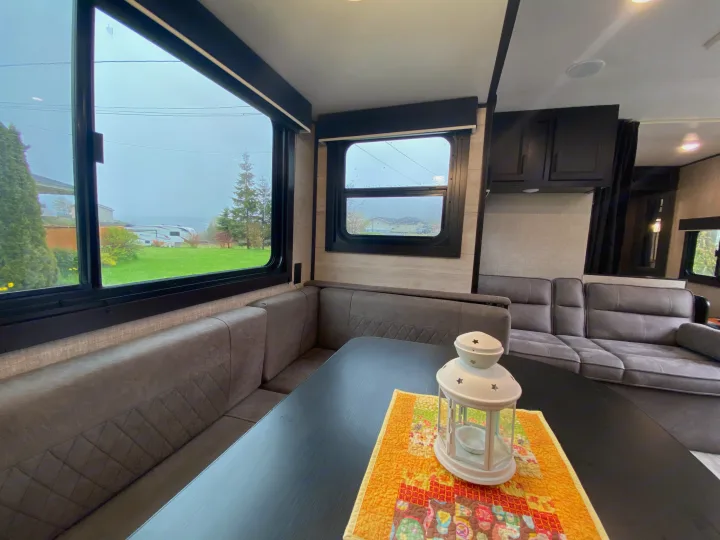 This bright RV rental interior features a cozy dinette, comfortable sofa, and large windows offering scenic outdoor views.. Jayco Jay Flight 2022