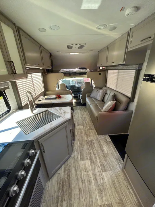 Spacious RV rental interior featuring a modern kitchen, dining area, comfortable sofa, and front cabin with bunk.. Thor Motor Coach Chateau 2024