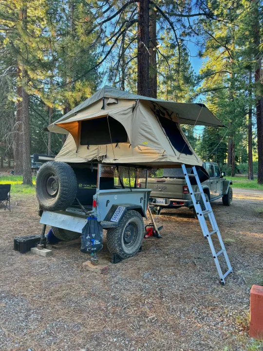 Overland camping setup: rooftop tent on trailer with a Jeep in a pine forest. Discover unique RV rental experiences!. Other Other 2020