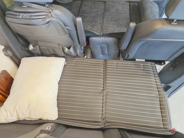 Custom sleeping setup in an RV rental, featuring a striped mattress pad and pillow for comfortable travel.. Mercedes-Benz Sprinter 2021