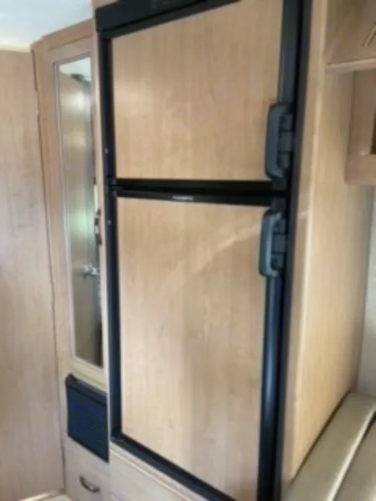 RV rental interior: A light wood-paneled refrigerator and mirrored cabinet provide essential RV kitchen amenities for travel.. Thor Four Winds 2020