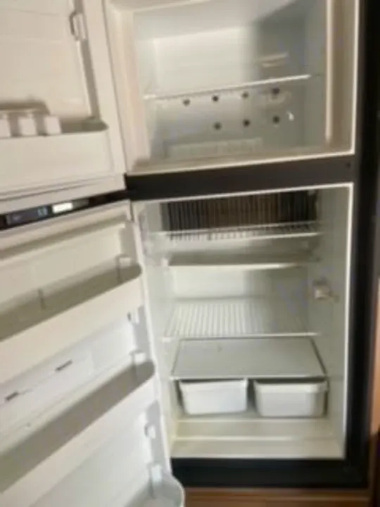 Inside an RV rental: a clean, empty refrigerator with shelves and bins, ready for your road trip provisions.. Thor Four Winds 2020