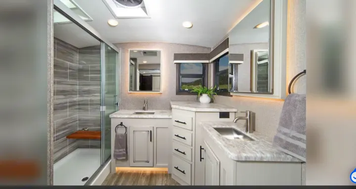 Spacious, modern RV rental bathroom featuring a large shower, dual vanity, and windows with scenic views, perfect for travel comfort.. Jayco North Point 2021