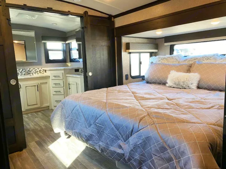 Cozy RV rental bedroom with connected bath, featuring a large bed, modern finishes & wood flooring.. Jayco North Point 2021