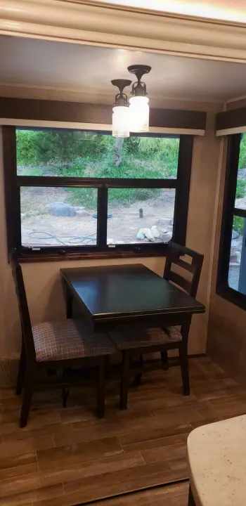 RV rental dining nook featuring a dark wood table, upholstered chairs, and outdoor views through large windows.. Jayco North Point 2021