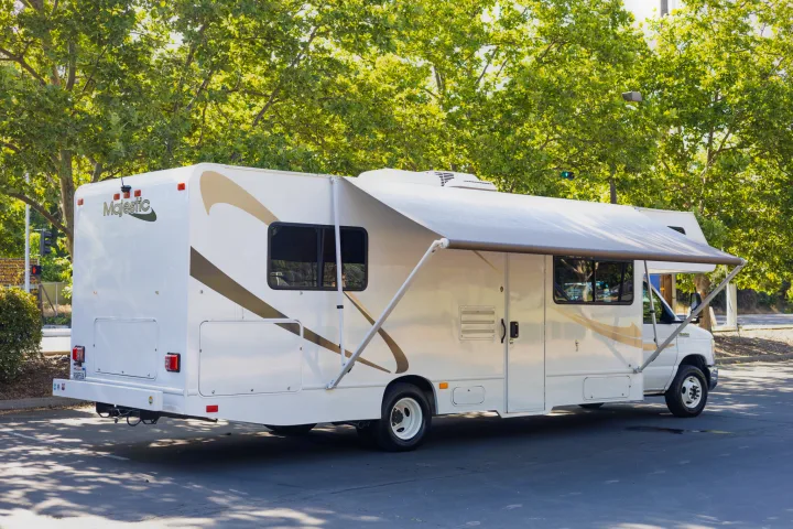 White Majestic Class C RV rental, awning extended, parked outdoors. Ideal for trips and adventures.. Thor Majestic 2015