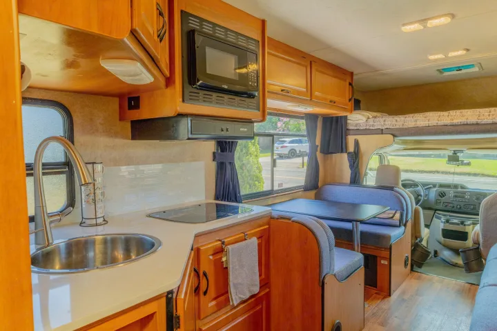 Bright rv rental interior featuring a full kitchen, dinette, and overhead bunk. Ideal for travel.. Thor Majestic 2015