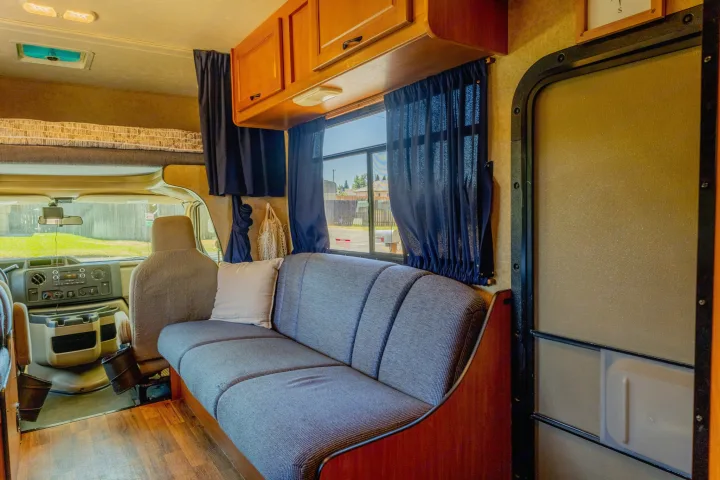 Spacious RV rental interior with front cockpit, cozy sofa, and overhead bed, perfect for your next adventure.. Thor Majestic 2015