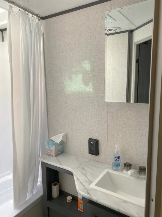 This RV rental bathroom offers a compact design with a shower, sink, mirror, and essentials like soap and tissues.. Aspen Trail Aspen Trail Trailer 2021