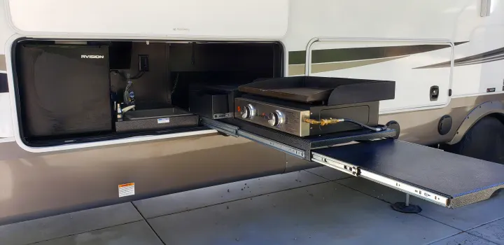 An extended outdoor kitchen from an RV rental, featuring a Blackstone griddle, RVISION refrigerator, and sink. Ready for mobile cooking.. Jayco North Point 2021