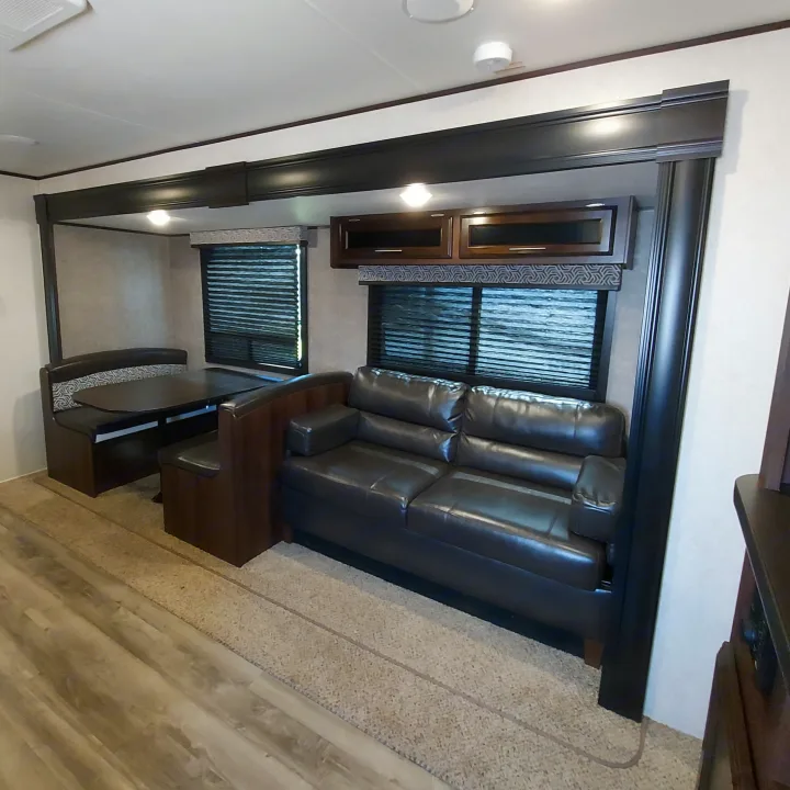 RV rental interior: a bright living area with a brown leather sofa, dinette, and overhead cabinets for a comfortable stay.. Jayco Jay Flight SLX8 2020