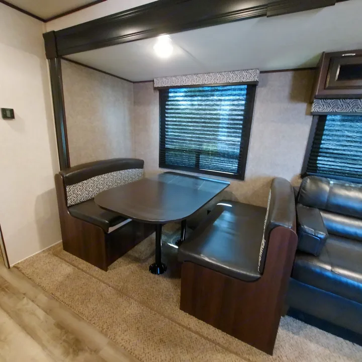 RV rental interior featuring a cozy dinette with patterned cushions and a dark table, plus a comfortable black sofa.. Jayco Jay Flight SLX8 2020