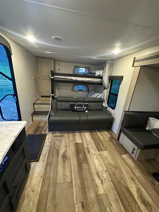 RV rental interior features bunk beds, a comfortable sofa, dinette, and wood-look flooring. Perfect for family trips.. Connect SE 2022