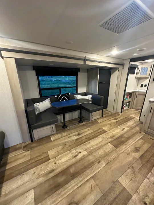 Spacious RV rental interior with a modern dinette, wood-look flooring, and compact kitchenette. Ready for travel.. Connect SE 2022