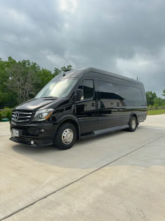 Black Mercedes-Benz Sprinter luxury RV rental van parked on concrete under an overcast sky.. Midwest Automotive Designs Super Sprinter 2019