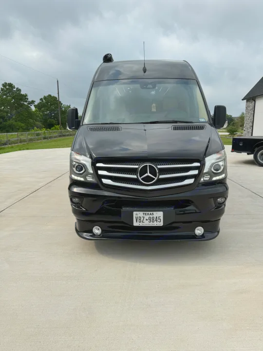 Front view of a black Mercedes Sprinter van, a sleek RV rental. Parked on concrete, it features a Texas license plate VBZ 9845.. Midwest Automotive Designs Super Sprinter 2019