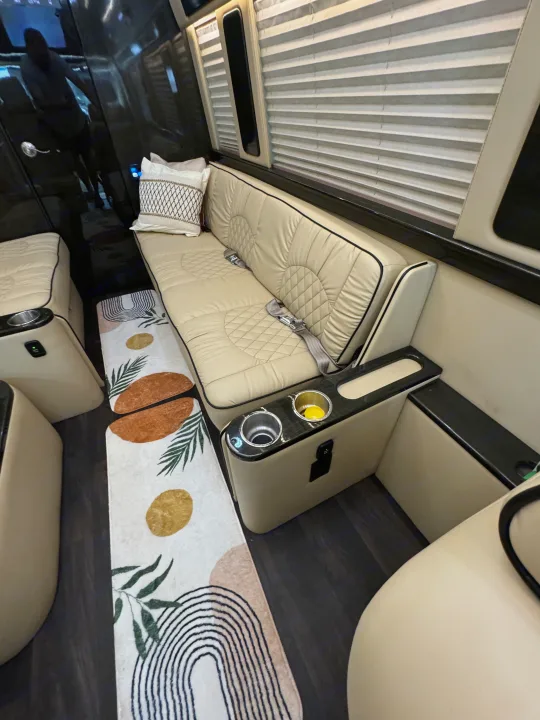 Luxury RV rental interior: comfortable beige bench seating with seatbelts, cup holders, charging port, and decorative rug.. Midwest Automotive Designs Super Sprinter 2019