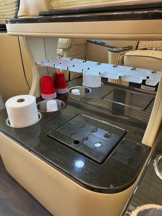 RV rental interior showcasing a dark wood counter with cup holders, paper towels, and covered storage compartments.. Midwest Automotive Designs Super Sprinter 2019