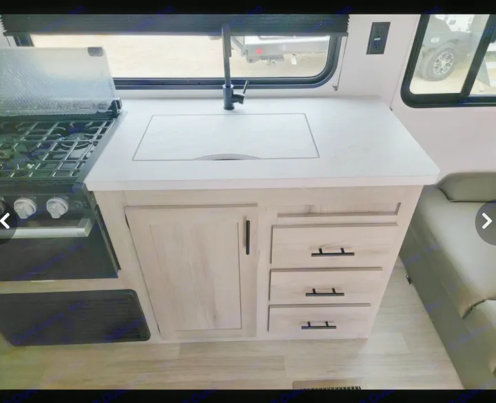 RV rental kitchen: Stove, integrated sink, bright countertop, and light wood cabinets & drawers with dark pulls.. Sportsmen SE 2023