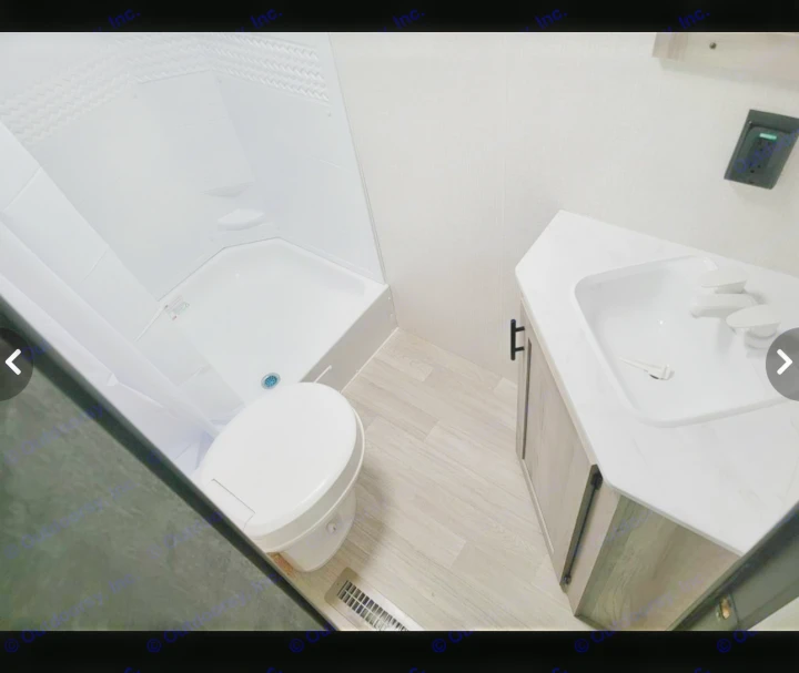 Clean RV rental bathroom: corner shower, toilet, and vanity with sink. Features light wood-look flooring and textured walls.. Sportsmen SE 2023