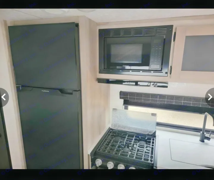 RV rental kitchen: black fridge, microwave, gas stove, and sink. Compact, functional for travel.. Sportsmen SE 2023