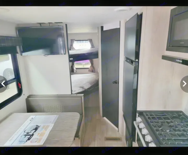 Explore this RV rental's cozy interior: kitchen with stove, fridge, dinette, TV, and bunk beds.. Sportsmen SE 2023