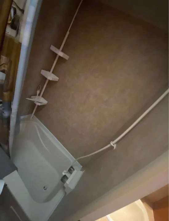 Inside an RV rental bathroom: view of a small tub, white shower caddy, and curtain rod.. Forest River Cherokee Grey Wolf 2012