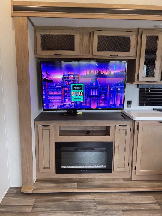 Cozy RV rental living space featuring a TV with Hulu, an electric fireplace, and light wood cabinetry.. Forest River Sabre 2024