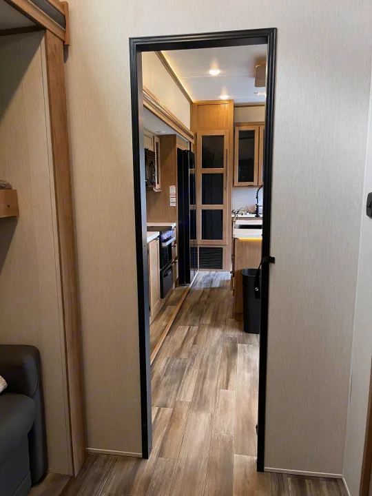 Inside a modern rv rental: bright kitchen with wood cabinetry, black appliances, and wood-look flooring.. Forest River Sabre 2024