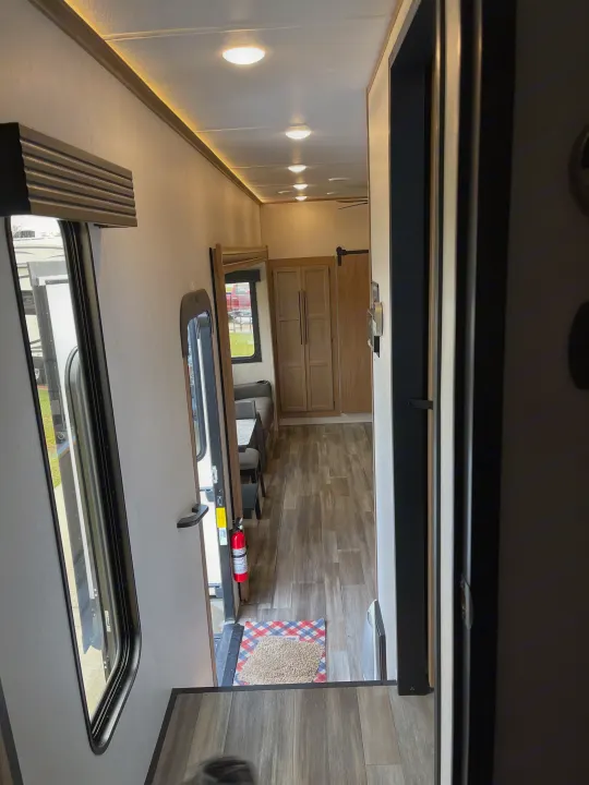 Modern RV rental interior with wood-look flooring, bright hallway, seating, and cabinets.. Forest River Sabre 2024